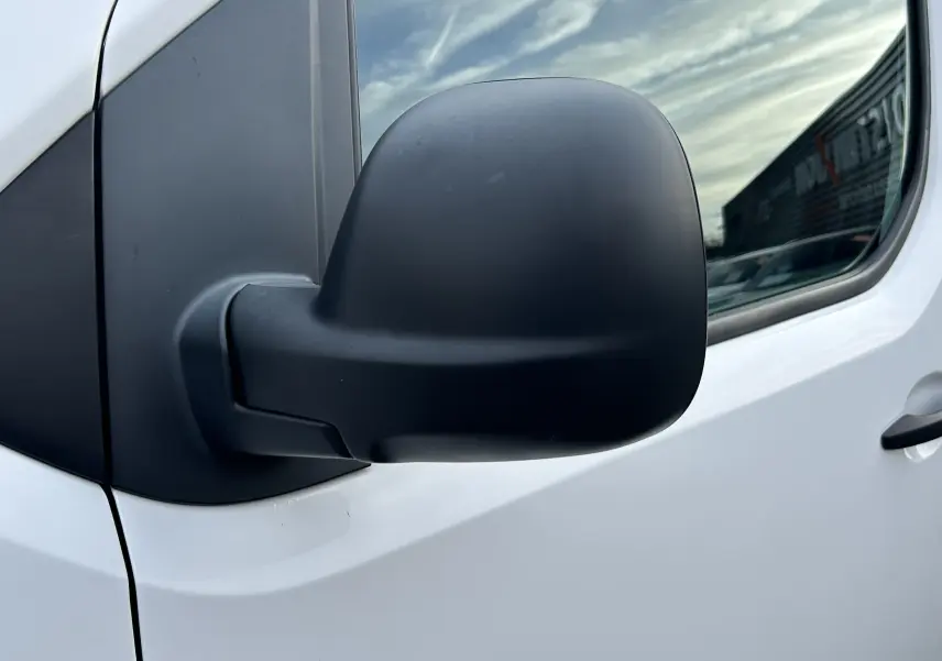 Gros plan sur le rétroviseur côté gauche du Citroën Jumpy blanc, avec reflet du ciel et bâtiment en arrière-plan.