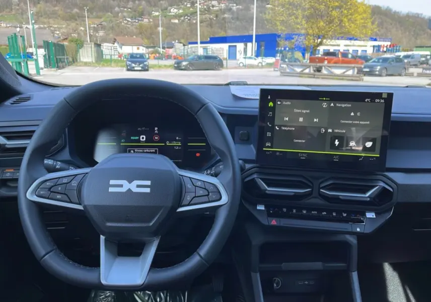 Vue intérieure du tableau de bord du Dacia Bigster Hybrid 155 Expression Plus, avec volant cuir et écran tactile central 10,1 pouces.