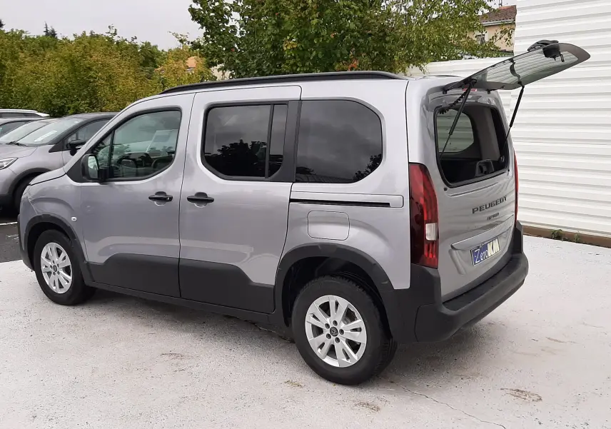 Peugeot Rifter gris acier vue 3/4 arrière droit avec lunette arrière ouverte et vitres arrière surteintées.