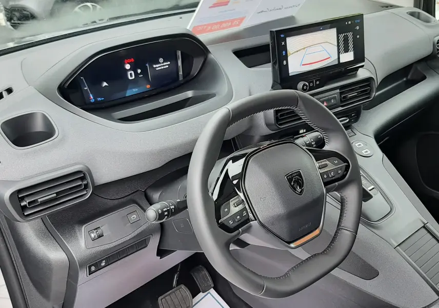 Vue intérieure côté conducteur du Peugeot Rifter gris acier 2026, avec tableau de bord numérique et écran tactile affichant la caméra de recul.