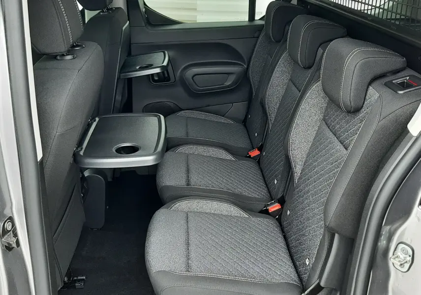 Vue latérale intérieure des sièges arrière gris tissu du Peugeot Rifter III Ph.2 avec tablette rabattable et cloison métallique.