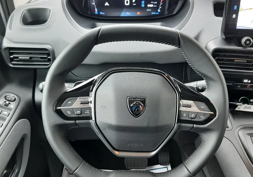 Vue frontale du volant noir et du tableau de bord numérique du Peugeot Rifter gris acier, avec écran tactile latéral visible.