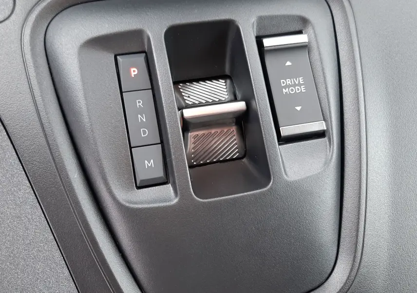 Gros plan sur la console centrale noire du Peugeot Rifter III Ph.2 avec commandes boîte auto et sélecteur Drive Mode.