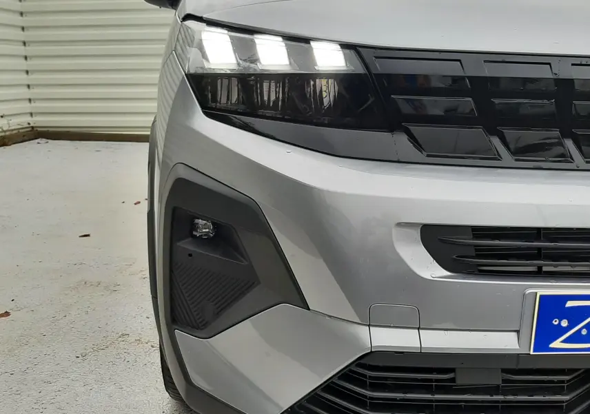 Vue avant gauche du Peugeot Rifter gris acier 2026 avec optiques LED et calandre noire distinctive.