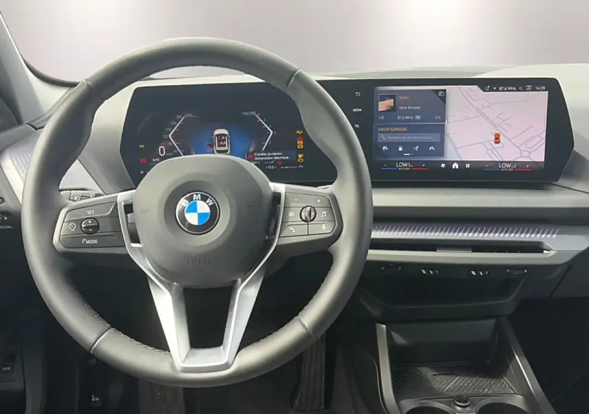 Vue intérieure centrée sur le volant cuir BMW et le tableau de bord numérique avec écran tactile panoramique.