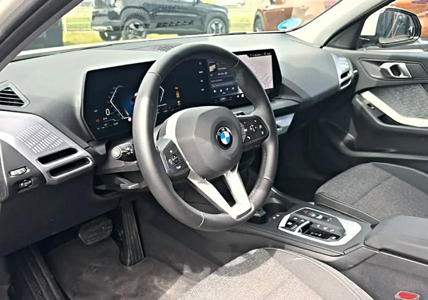 Vue intérieure côté conducteur de la BMW Série 1 120da 2025 avec volant cuir M et écran numérique moderne.