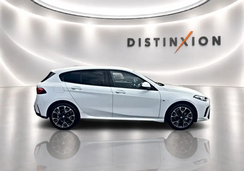 BMW Série 1 blanche vue de profil côté gauche dans un showroom lumineux avec jantes sport noires.