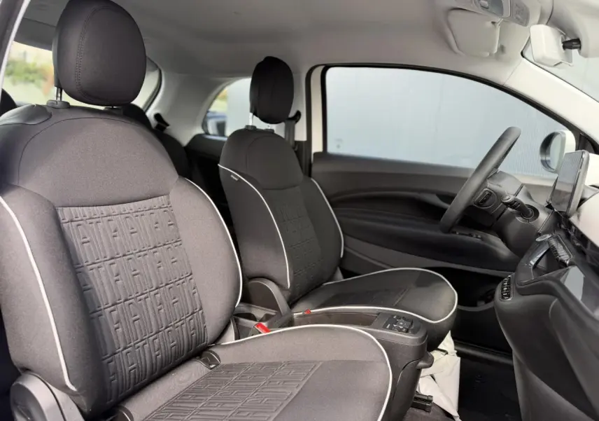 Vue intérieure côté droit de la Fiat 500 électrique 2024, sièges tissu noir Seaqual avec surpiqûres blanches et tableau de bord assorti.