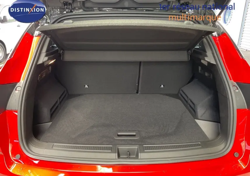 Coffre ouvert d'un Renault Austral E-Tech Full Hybrid rouge passion avec toit noir, vue arrière montrant l'espace de chargement vide.