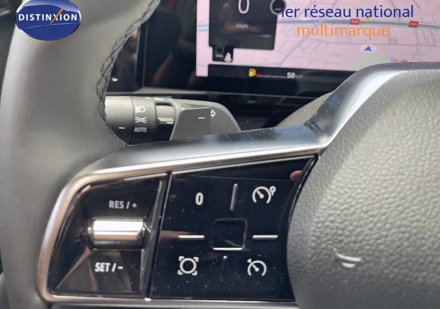 Gros plan sur les commandes au volant du Renault Austral E-Tech Hybrid 2025, avec écran numérique en arrière-plan.
