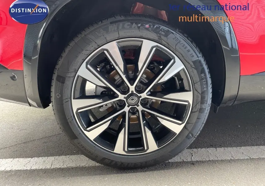 Gros plan sur la roue avant gauche du Renault Austral rouge passion avec jante alliage bicolore moderne.