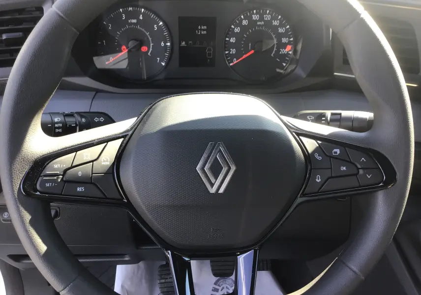 Vue rapprochée du volant noir du Renault Master 2025 avec commandes intégrées et tableau de bord visible en arrière-plan.