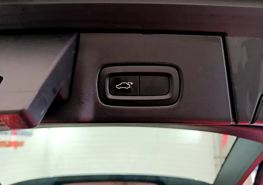 Bouton d'ouverture électrique du coffre sur la partie intérieure du hayon d'un Volvo V90 Cross Country bleu.