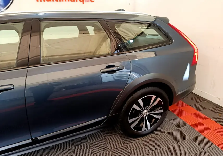 Vue latérale droite du Volvo V90 Cross Country bleu, mettant en valeur la roue arrière et les lignes élégantes du break.
