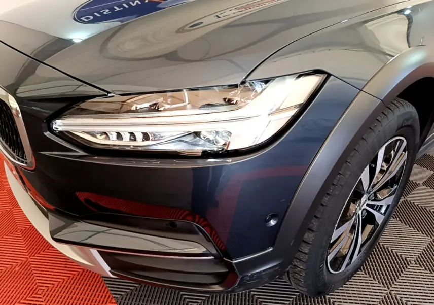 Gros plan sur l'avant droit bleu du Volvo V90 Cross Country 2019, mettant en valeur le phare LED et la jante alliage.