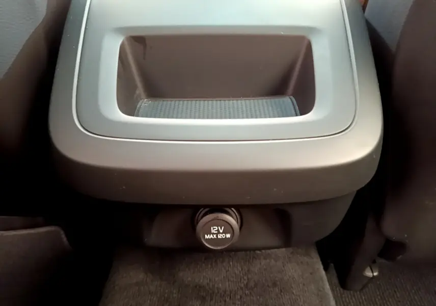 Prise 12V noire vue de face sous un rangement central intérieur du Volvo V90 Cross Country bleu 2019.