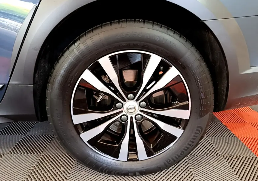 Gros plan sur la roue avant droite du Volvo V90 Cross Country bleu, jante alliage noir et argentée.