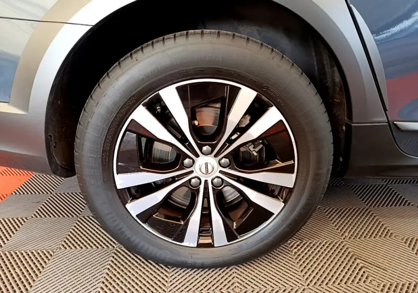 Gros plan sur la roue avant droite de la Volvo V90 Cross Country bleu, avec jante alliage noir et argentée.