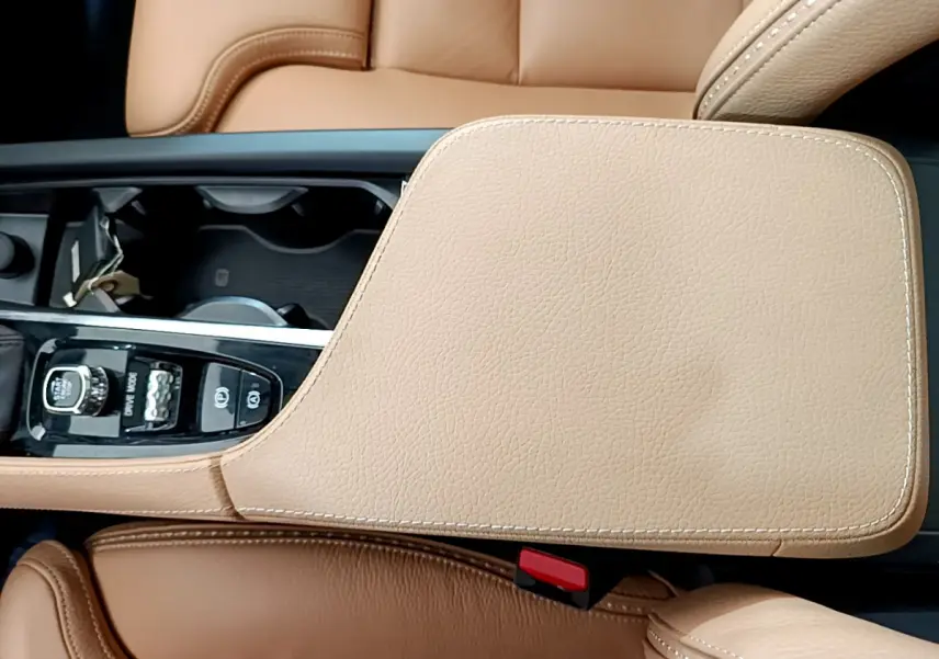 Vue rapprochée de la console centrale beige et des sièges en cuir marron clair d'un Volvo V90 Cross Country.