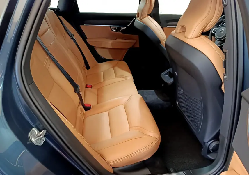 Vue intérieure côté gauche des sièges arrière en cuir beige du Volvo V90 Cross Country bleu, avec porte ouverte.