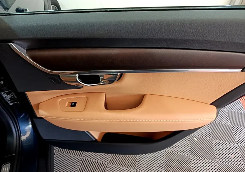 Intérieur côté gauche de la porte d’une Volvo V90 Cross Country bleu, garniture cuir beige et insert bois foncé.