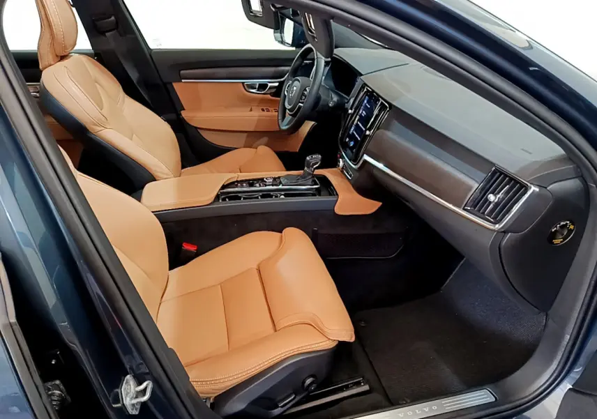 Intérieur avant droit du Volvo V90 Cross Country bleu, sièges cuir beige et tableau de bord moderne avec écran tactile.