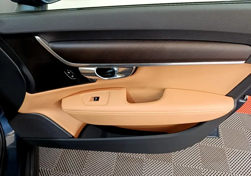 Vue intérieure côté gauche de la porte avant beige et bois foncé du Volvo V90 Cross Country bleu 2019.