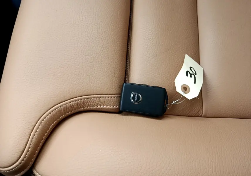 Gros plan sur une clé Volvo noire posée sur un siège en cuir beige clair, intérieur du Volvo V90 Cross Country.