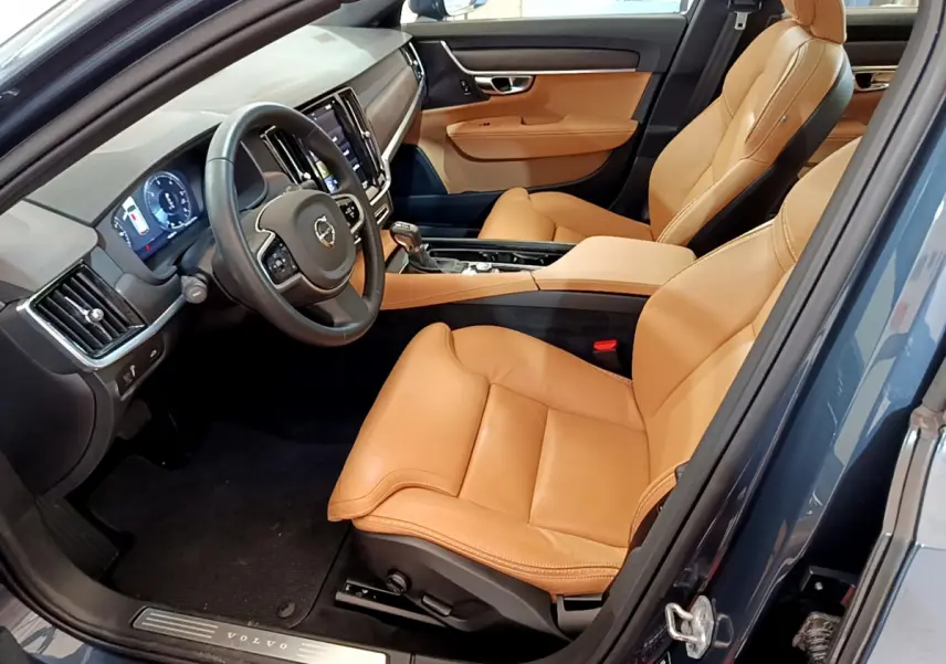 Vue intérieure côté conducteur de la Volvo V90 Cross Country bleu, sièges cuir beige et tableau de bord moderne.