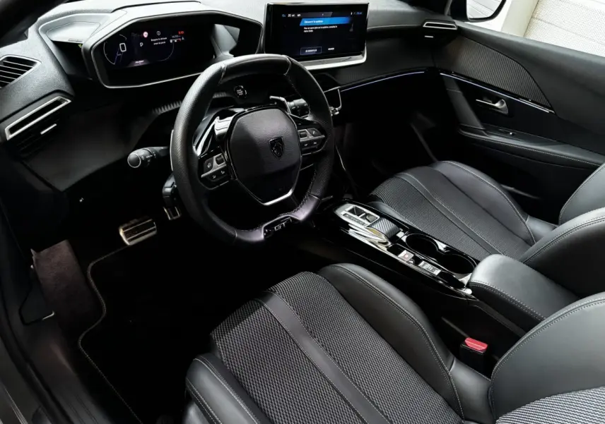 Intérieur Peugeot 208 Hybrid 136 GT vu côté conducteur, avec tableau de bord numérique et finitions noires élégantes.