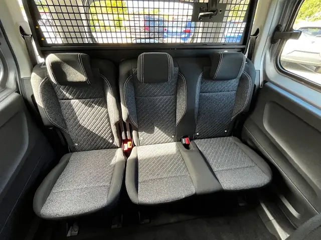 Vue intérieure arrière du Peugeot Rifter 2024 gris foncé, montrant la banquette trois places avec sièges en tissu gris à motifs.