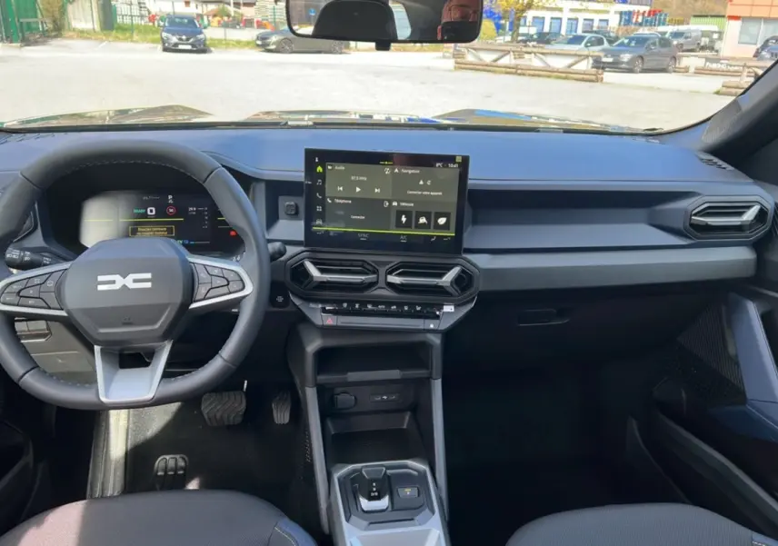 Vue intérieure du tableau de bord et volant cuir du Dacia Bigster Hybrid 155 Expression Plus avec écran tactile central.
