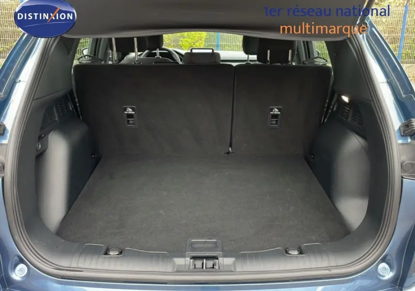 Coffre ouvert vu de l'arrière d'un Ford Kuga 2024 bleu vapor metal, montrant un espace de chargement propre et spacieux.