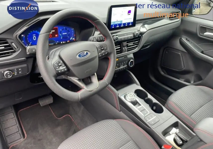 Vue intérieure côté conducteur du Ford Kuga 2024, volant cuir perforé avec surpiqûres rouges et console centrale moderne.