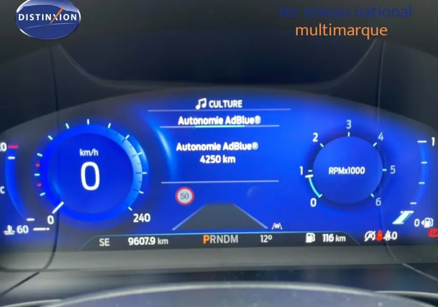 Tableau de bord numérique bleu du Ford Kuga 2024 affichant vitesse, régime moteur et autonomie AdBlue.