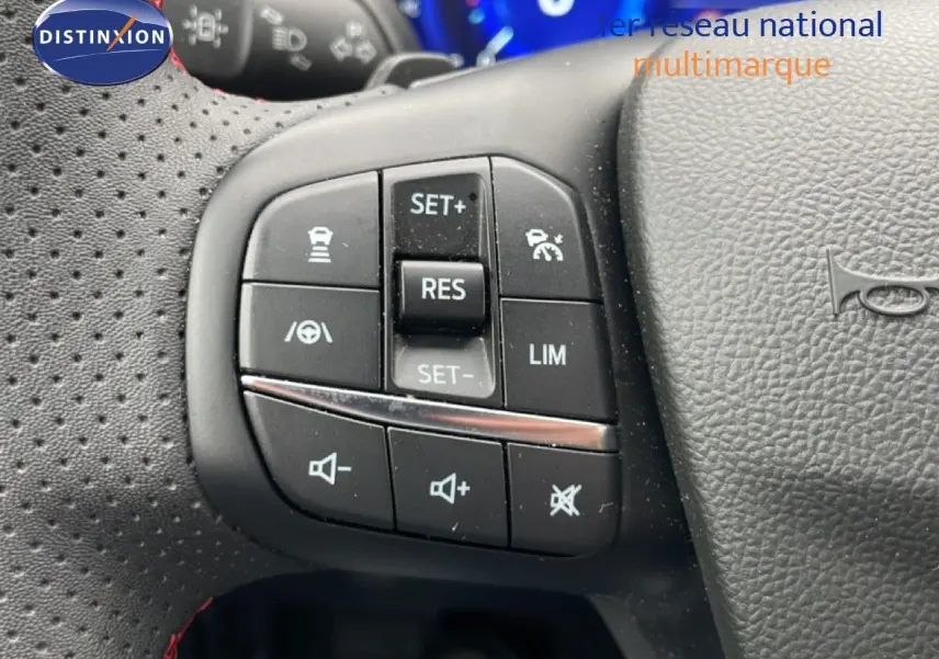 Gros plan sur les commandes au volant du Ford Kuga 2024 bleu Vapor Metal, avec boutons de régulateur et volume sonore.