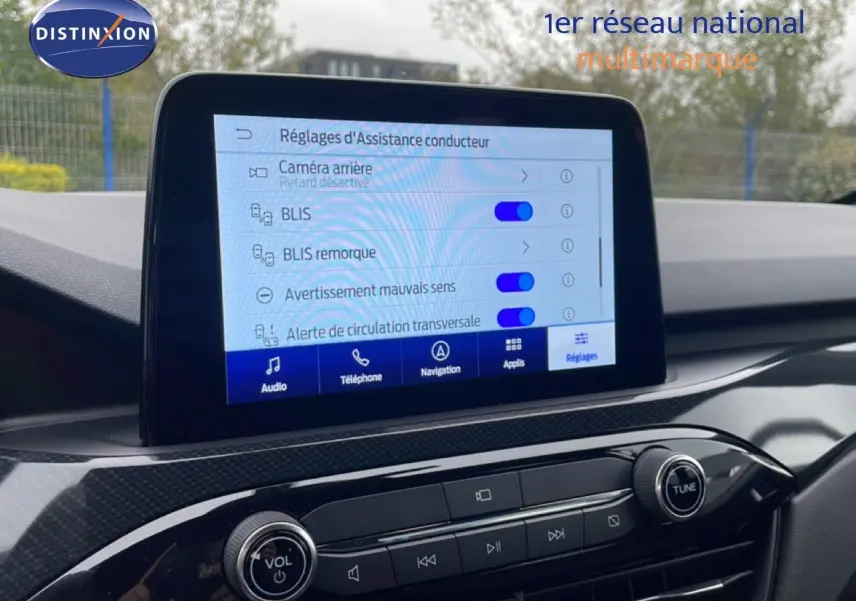 Vue intérieure centrée sur l'écran tactile du tableau de bord du Ford Kuga 2024, affichant les réglages d'assistance conducteur.