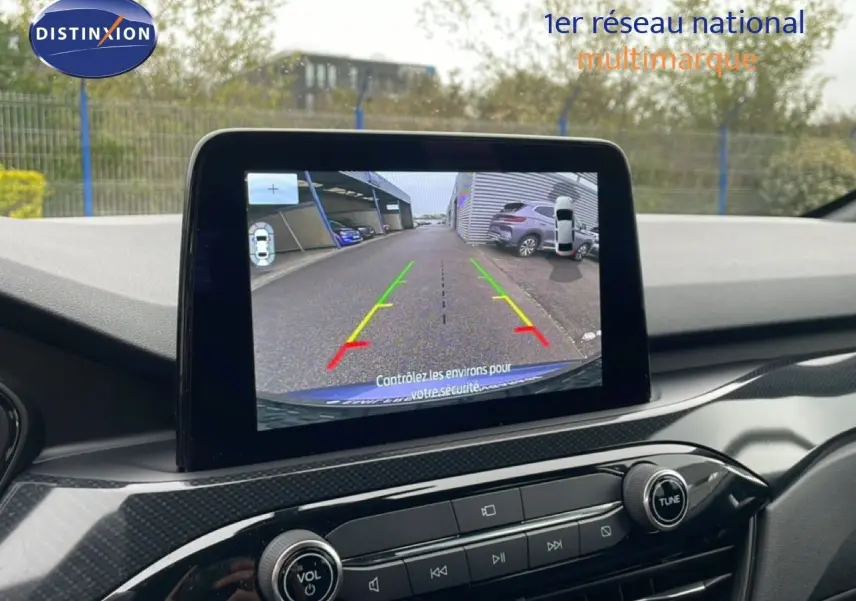Écran central montrant la caméra de recul du Ford Kuga bleu Vapor Metal, avec vue arrière et lignes de guidage colorées.