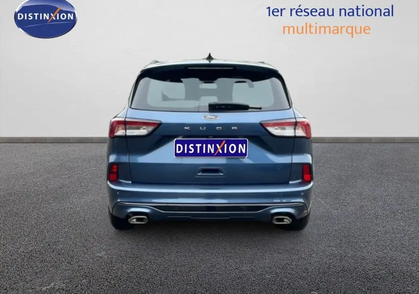 Vue arrière d'un Ford Kuga 2024 bleu Vapor Metal avec double sortie d'échappement et logo Distinxion visible.