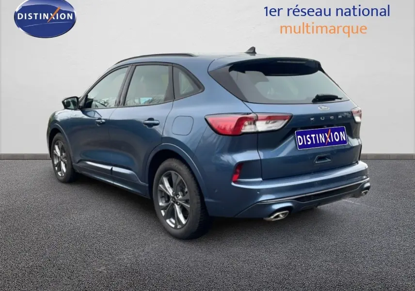 Ford Kuga 2024 bleu Vapor Metal vu en 3/4 arrière droit, avec feux LED et double sortie d’échappement chromée.