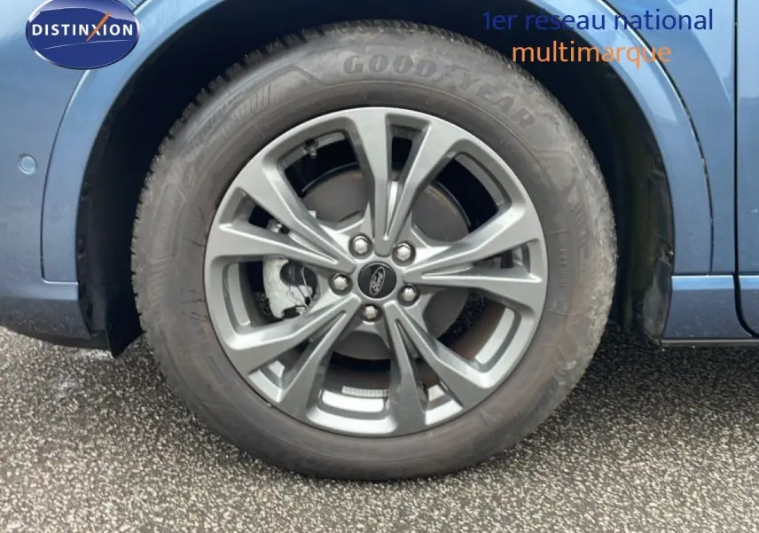 Gros plan sur la roue avant droite du Ford Kuga 2024 bleu Vapor Metal avec jante alliage et logo Ford central.
