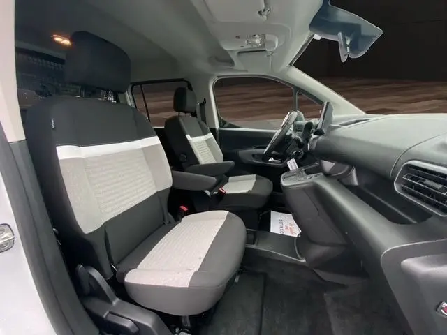 Vue intérieure côté conducteur du Citroën Berlingo 2025, sièges bi-ton gris et noir avec accoudoir central.
