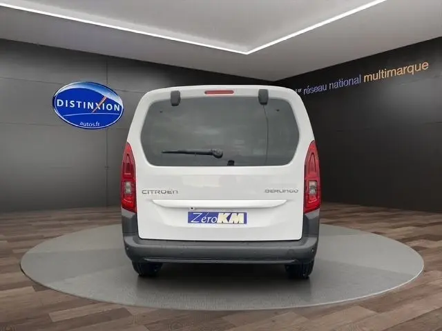 Vue arrière d'un Citroën Berlingo blanc 2025 dans un showroom avec logo Distinxion en arrière-plan.
