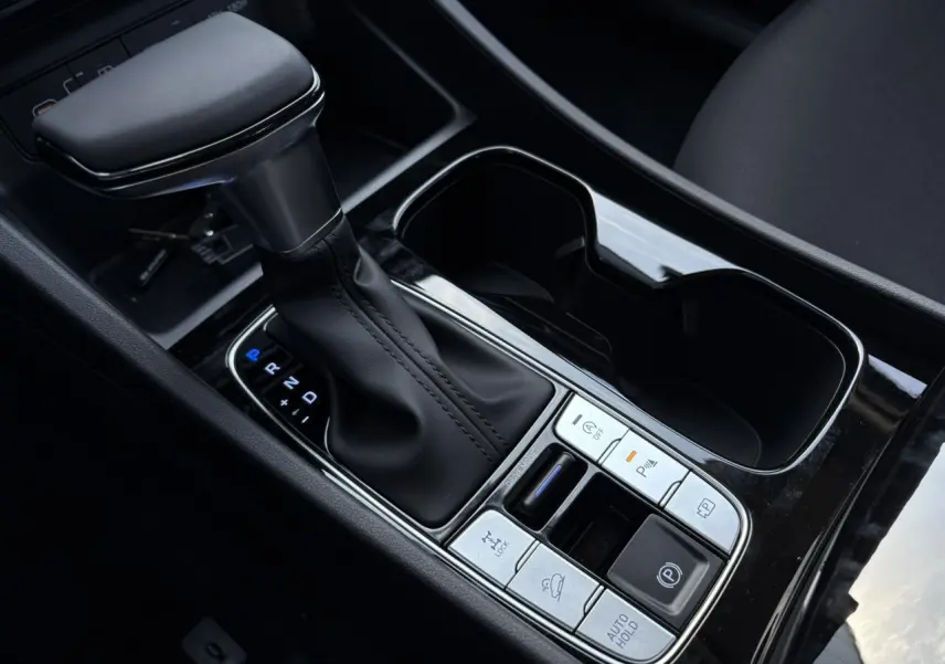 Gros plan sur la console centrale noire du Hyundai Tucson 2025 avec levier de vitesses automatique et commandes intégrées.