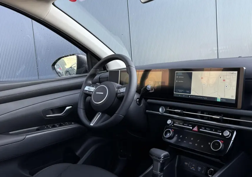 Intérieur du Hyundai Tucson 2025 vu côté conducteur, tableau de bord noir avec écran tactile large et volant cuir.