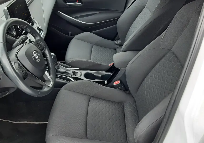 Intérieur de la Toyota Corolla 122 CH DYNAMIC 2022 vue côté conducteur, sièges tissu gris et tableau de bord moderne.