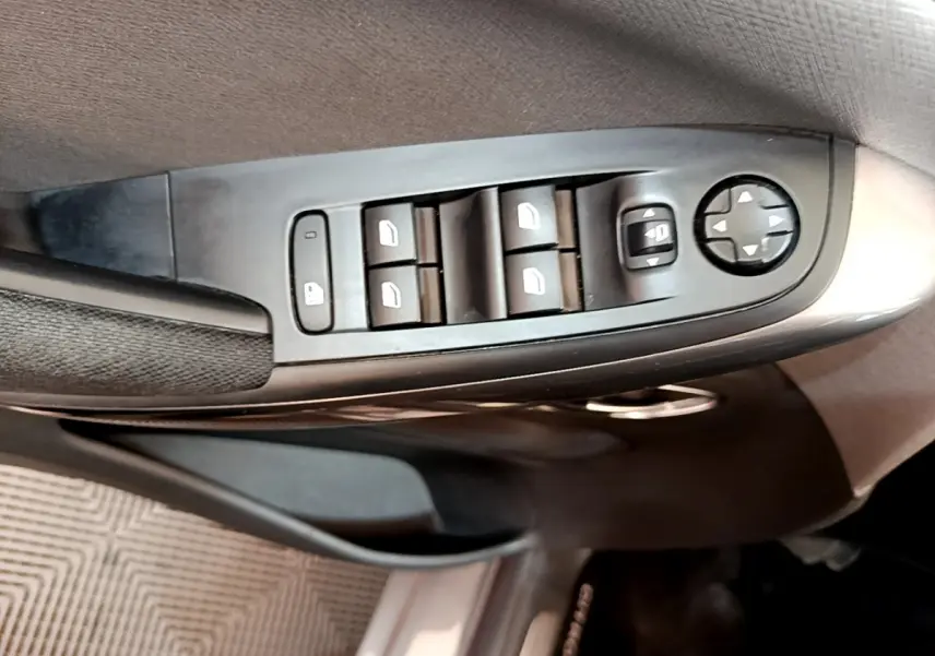 Gros plan sur les commandes de lève-vitres et réglage des rétroviseurs côté conducteur du Citroën Grand C4 SpaceTourer gris foncé.