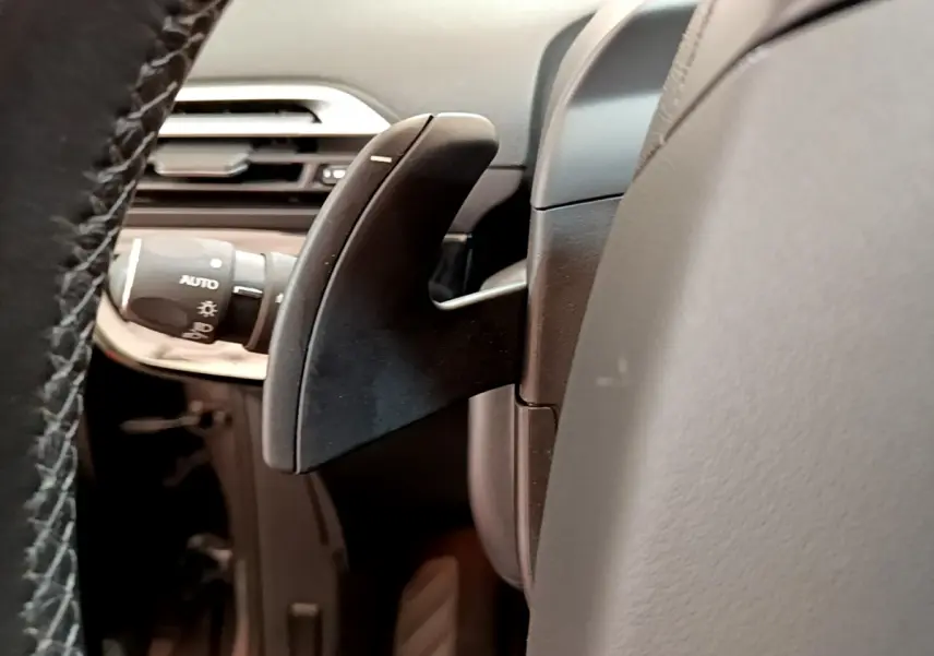 Gros plan sur la palette de changement de vitesse derrière le volant cuir du Citroën Grand C4 SpaceTourer gris foncé.