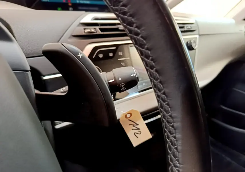 Gros plan intérieur sur le volant cuir et palettes de changement de vitesse du Citroën Grand C4 SpaceTourer gris foncé 2022.