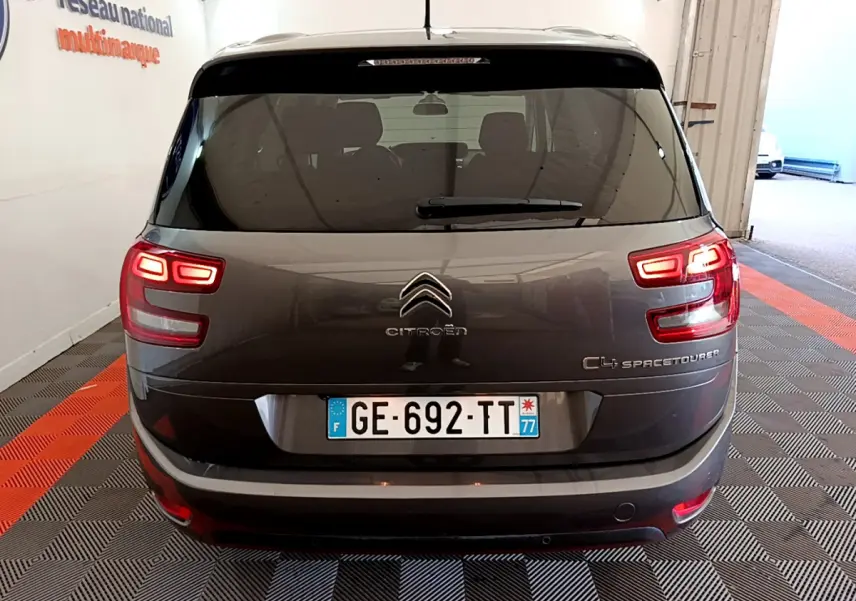 Vue arrière d'un Citroën Grand C4 Spacetourer gris foncé avec feux allumés dans un garage fermé.